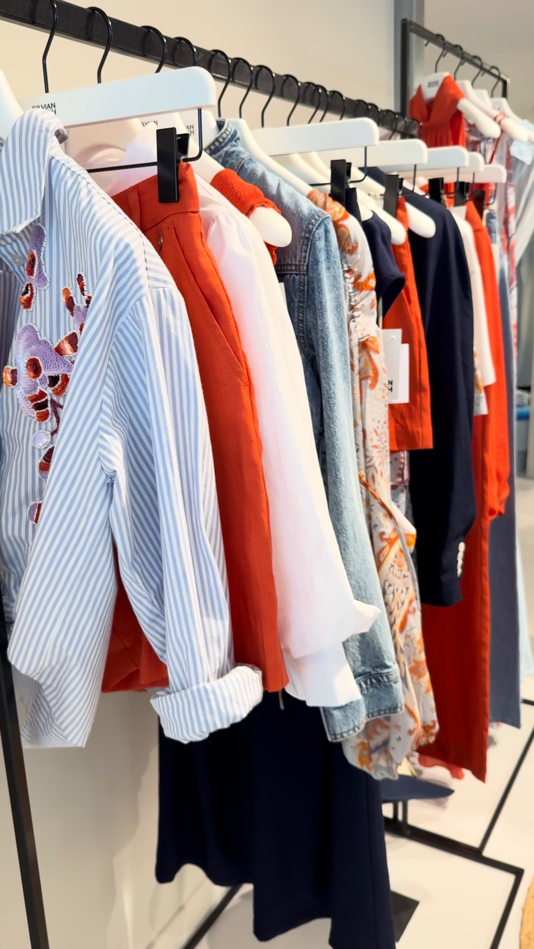 Kledingrek met de collectie van Pastelle in oranje, blauw en wit
