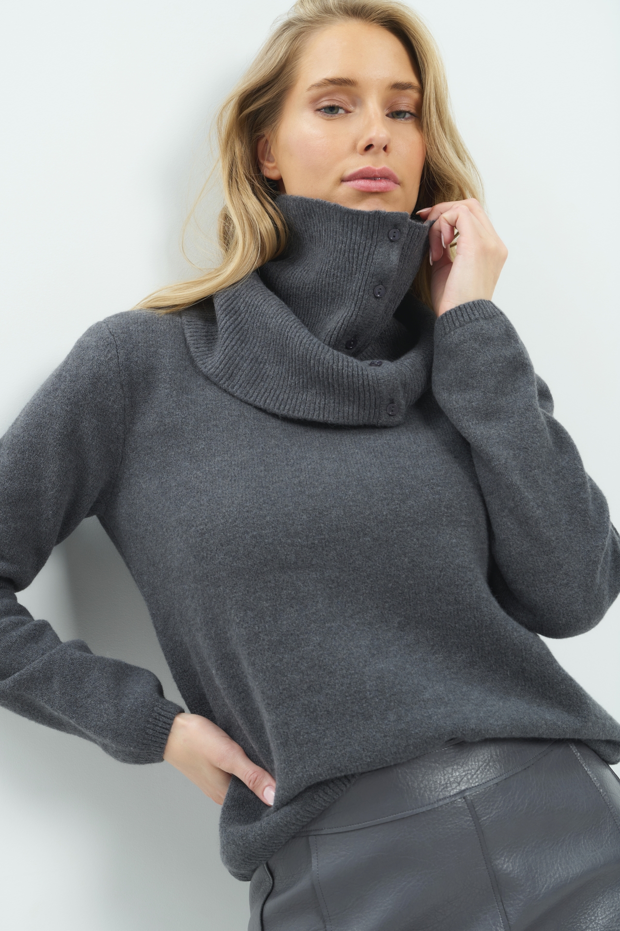 Model in een gebreide trui van YAYA met een losse col en knoopjes in antraciet melange