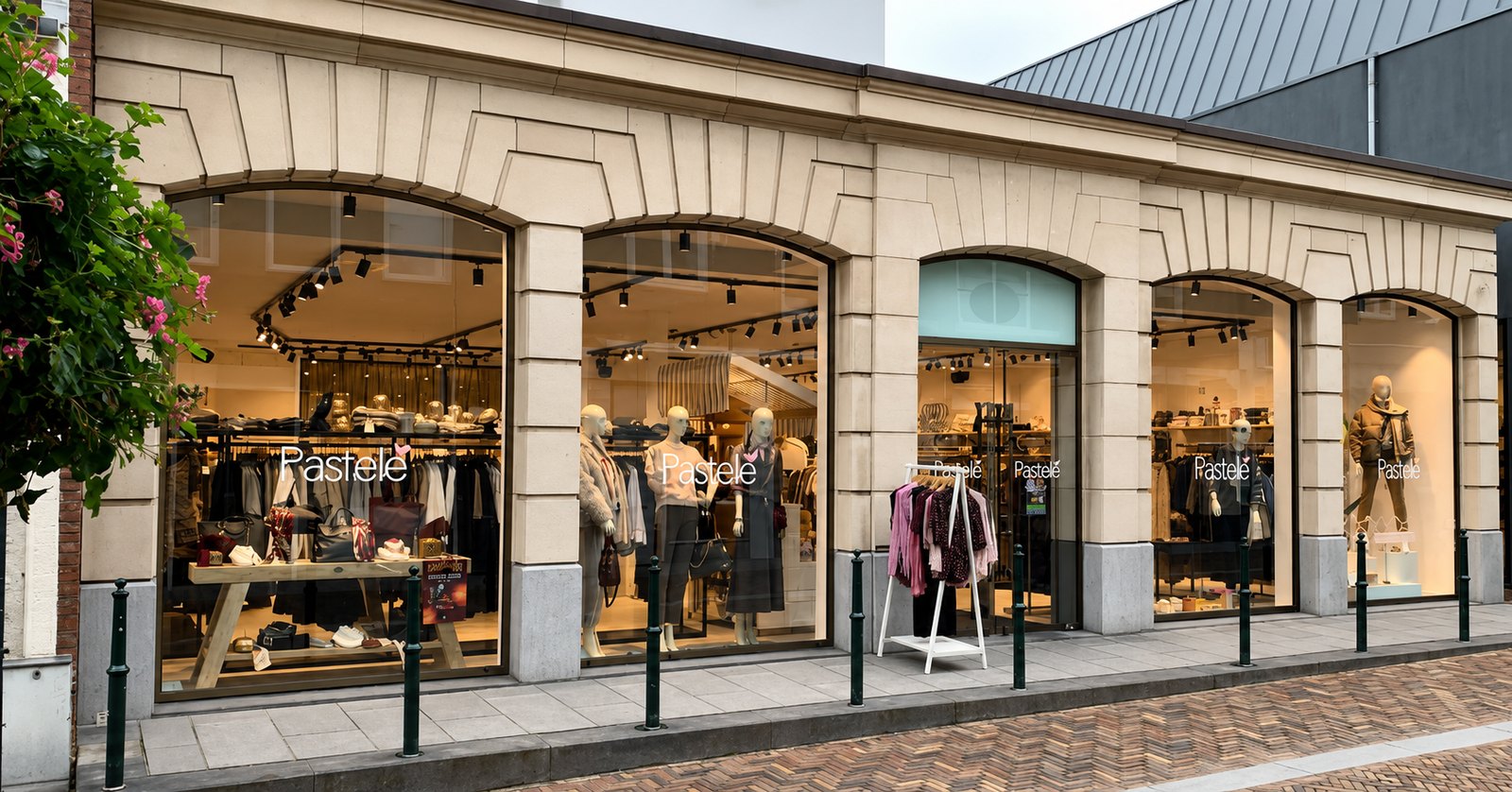 De gevel van Pastelle Wassenaar aan de Langstraat, met verlichte etalages achter ronde bogen