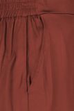 Satinlook broek van het merk Studio Anneloes met elastieken tailleband, steekzakken voor, faux papselzakken achter en een rechte wijde pijp in de kleur terra.